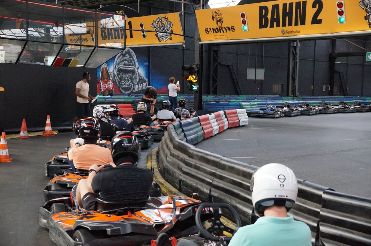Teilnehmende in Karts vor dem Start auf der Indoor-Kartbahn